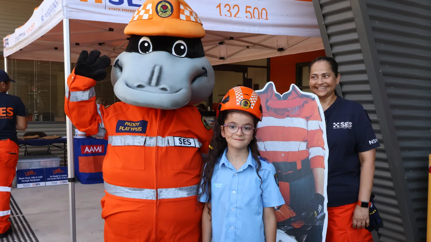 Paddy the platypus and a volunteer with a child at a community event