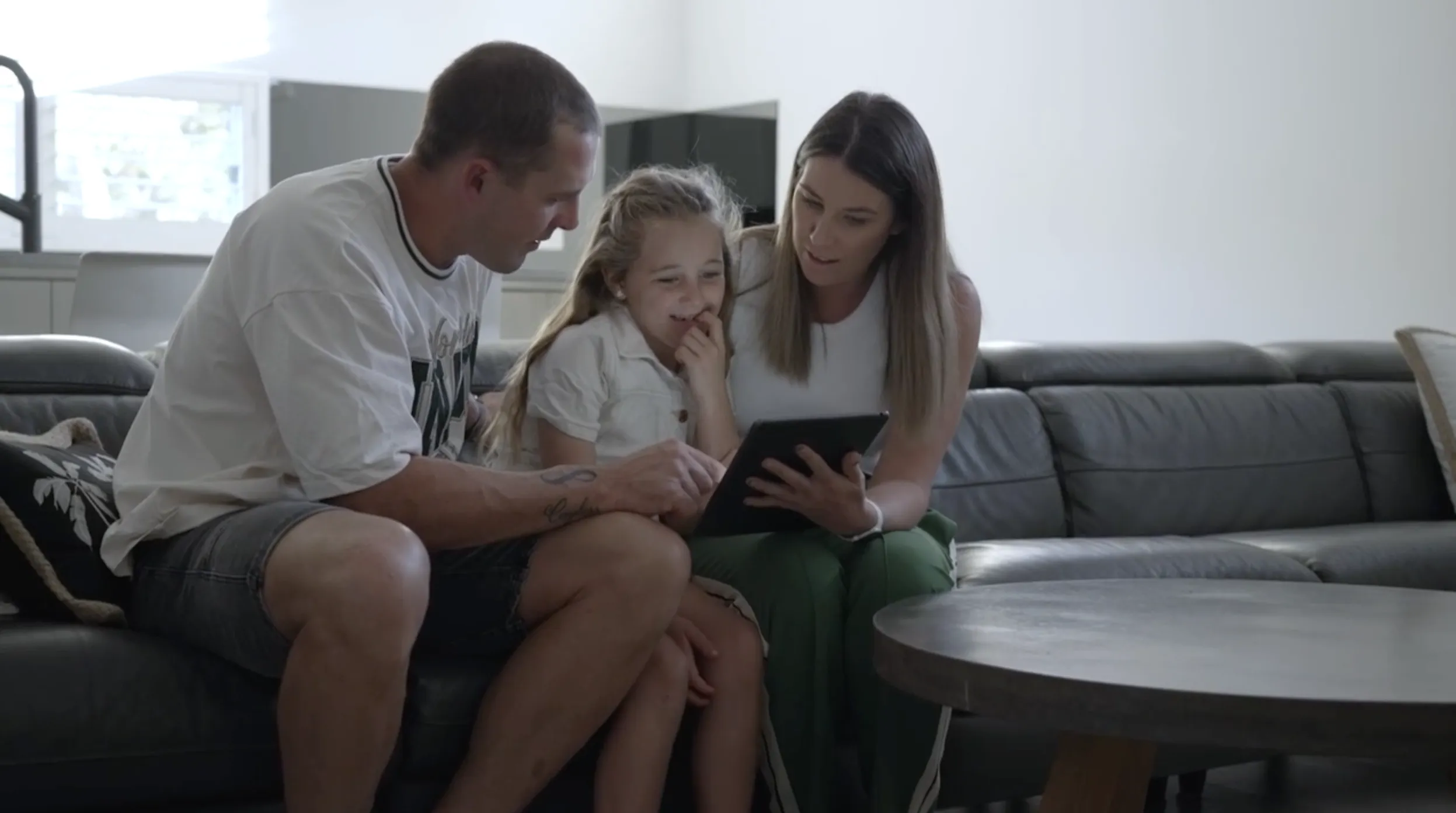 A family is gathered on the couch going through their emergency plan on a tablet
