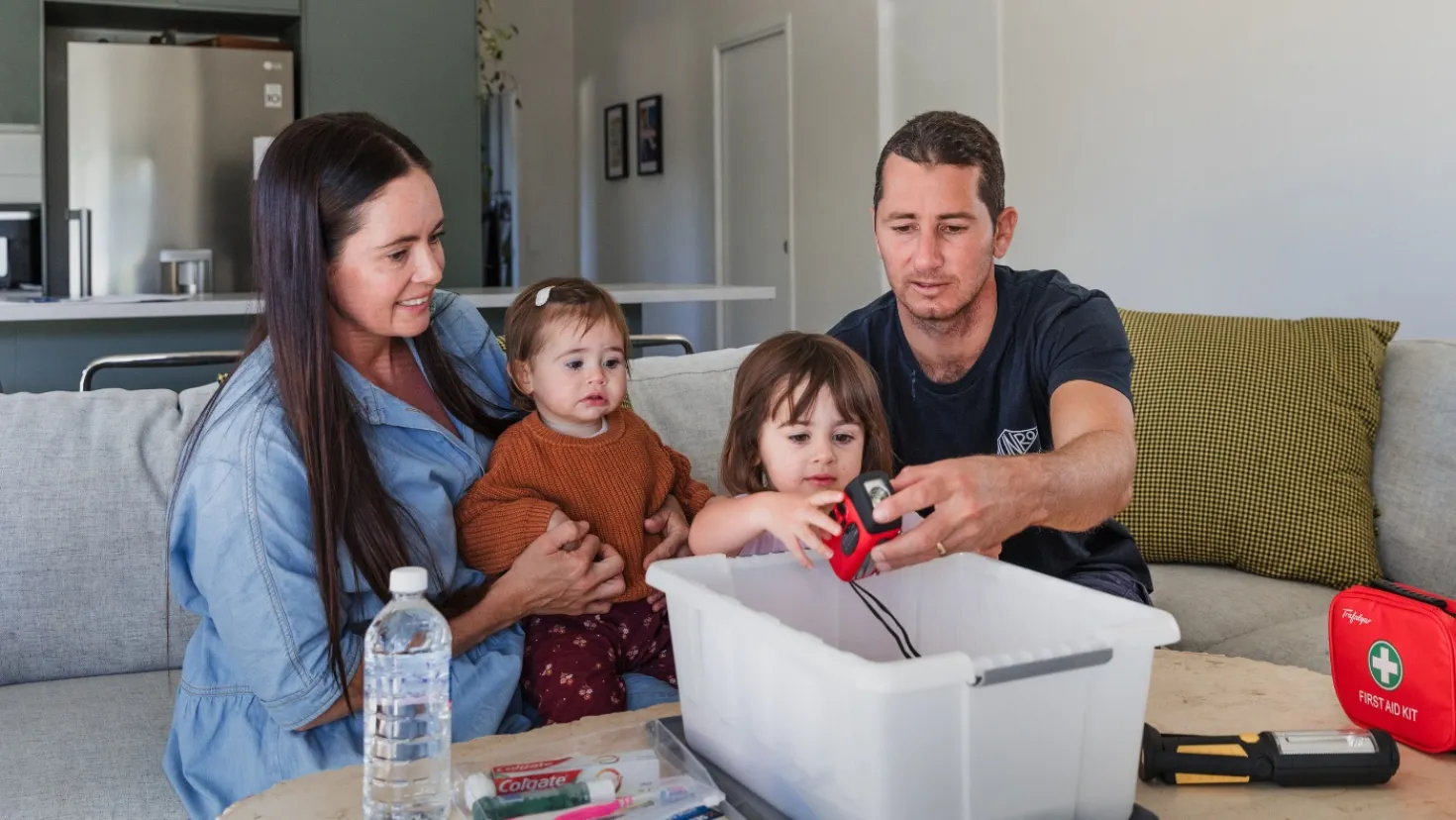 A couple and their two kids packing an emergency kit in their living room. 