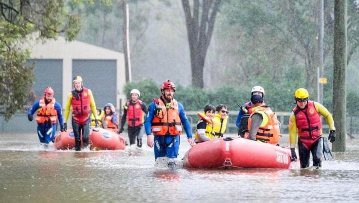 NSW SES Volunteers conducting a rescue operation in a flooded area using two boats.
