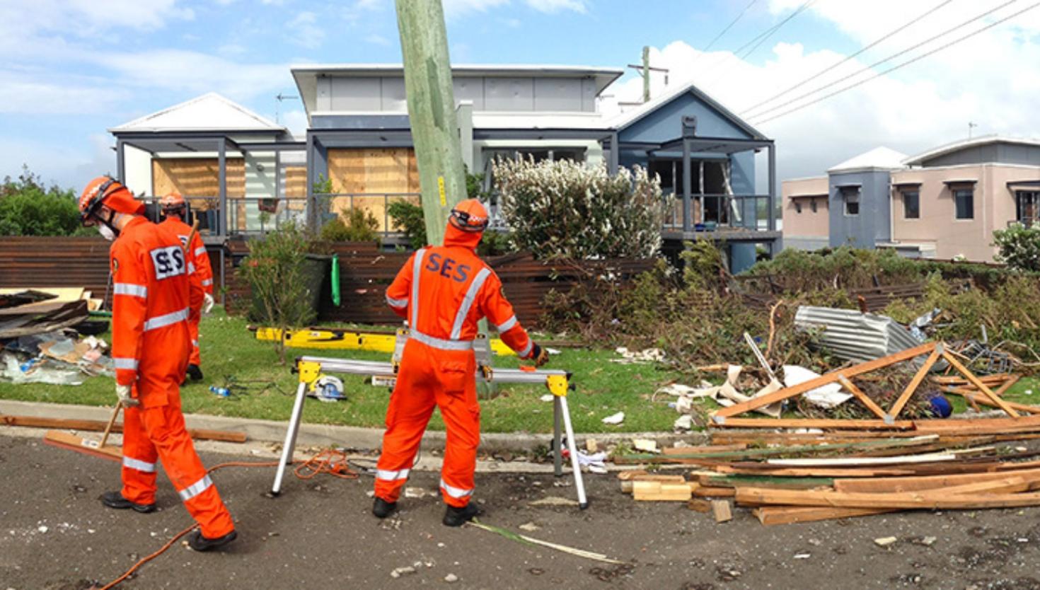 NSW SES members assess damage in front of a house after a storm.