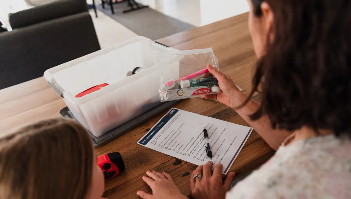 Woman and children preparing an emergency kit using a checklist as a guide.