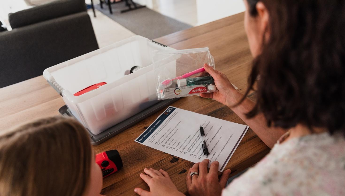 Woman and children preparing an emergency kit using a checklist as a guide.