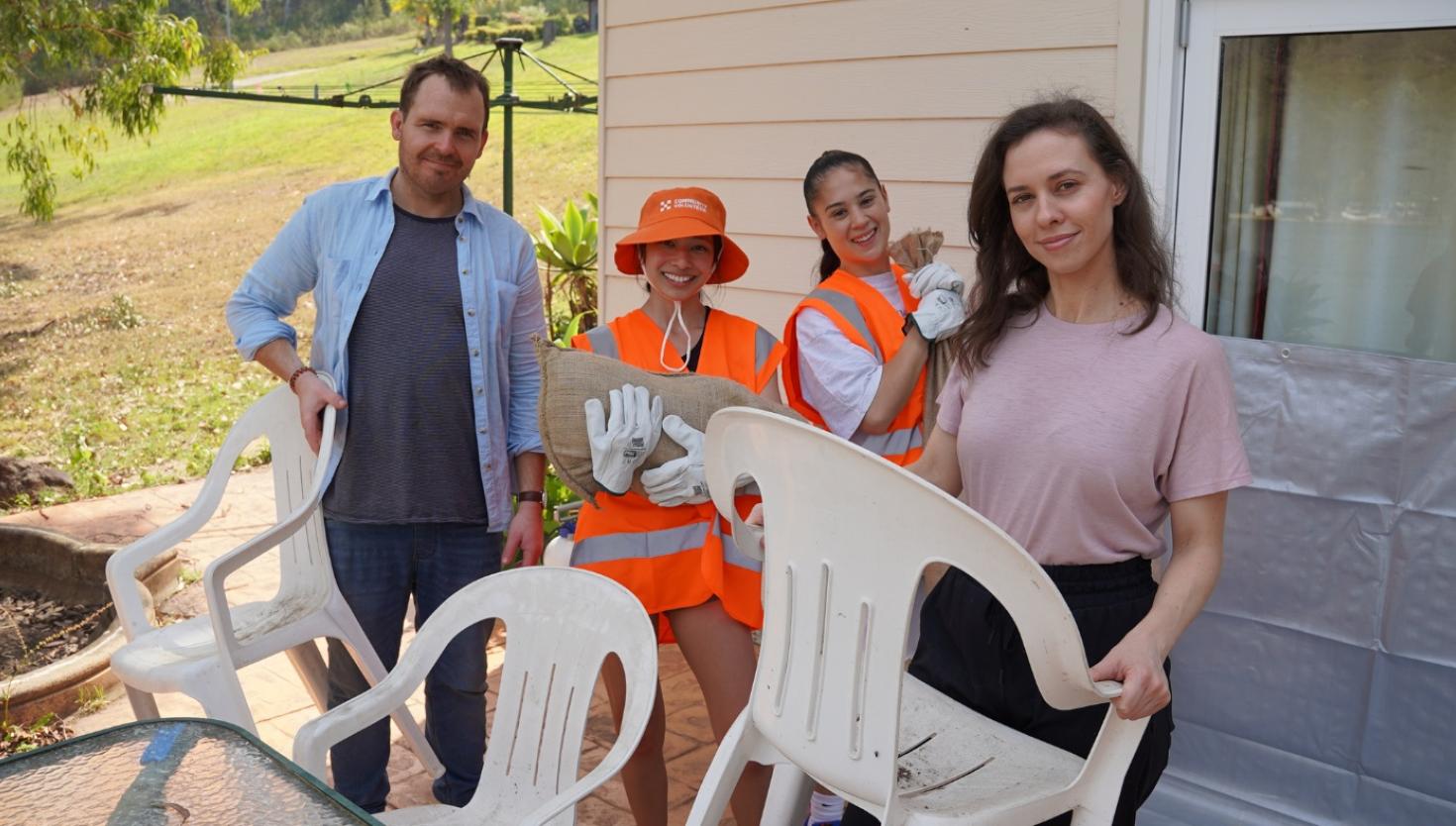 Four Spontaneous volunteers working together holding sandbags and chairs.