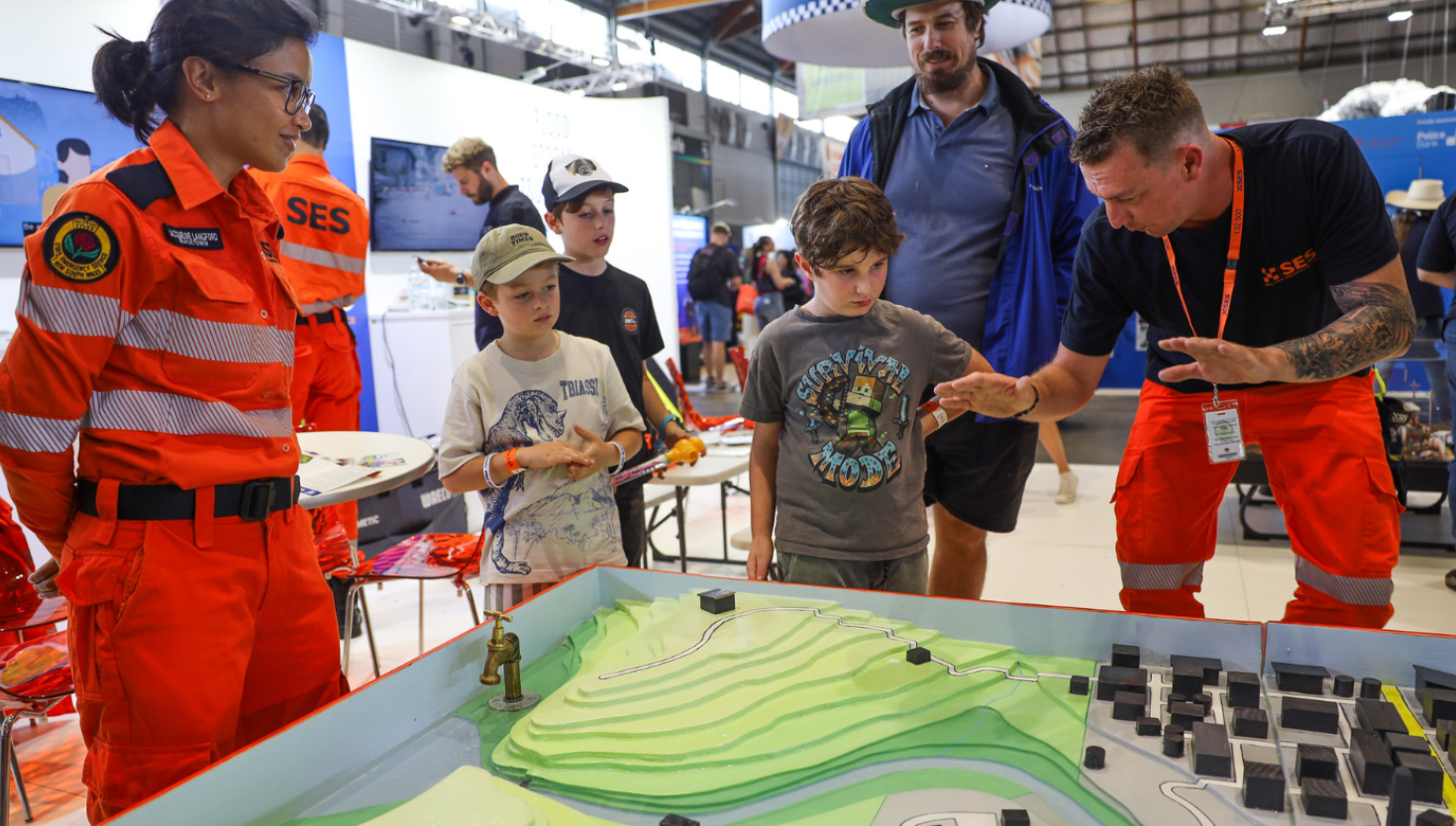 NSW SES members demonstrating information on a display model at expo to guests attending the display