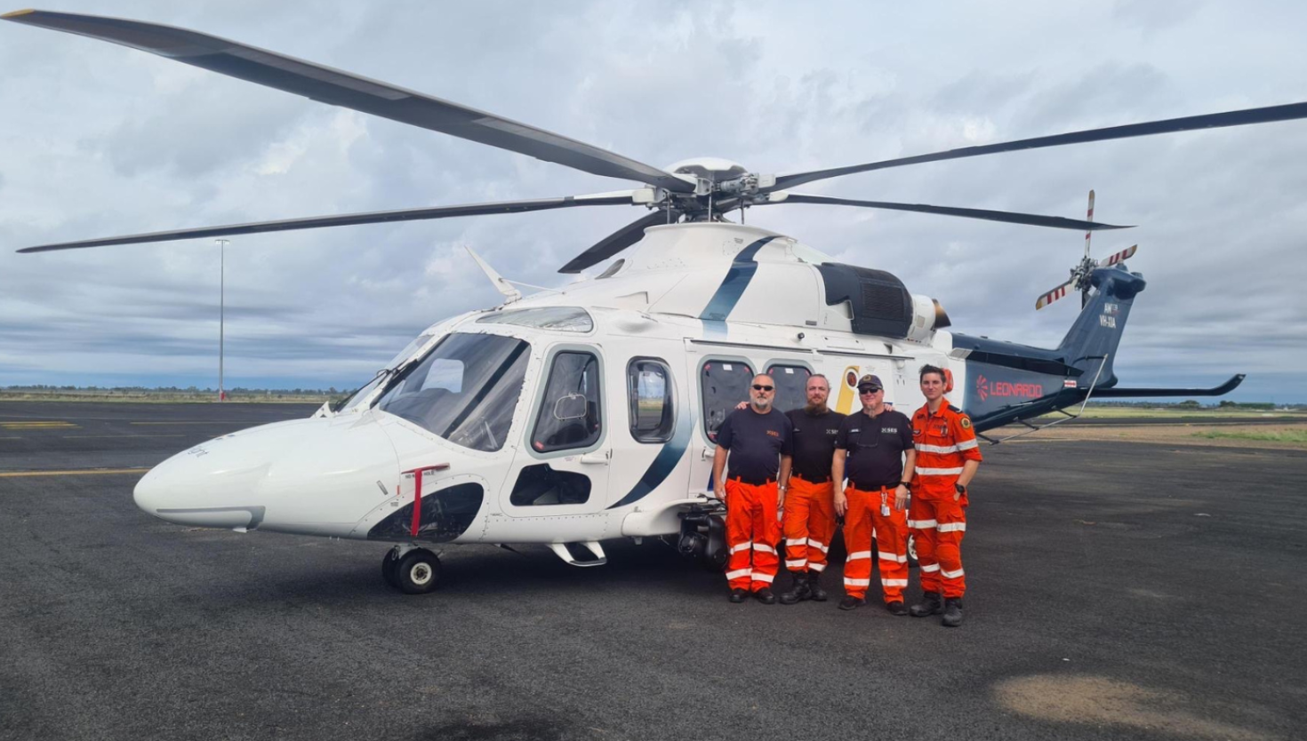 Four NSW SES volunteers stand next to a helicopter in the Moree area.