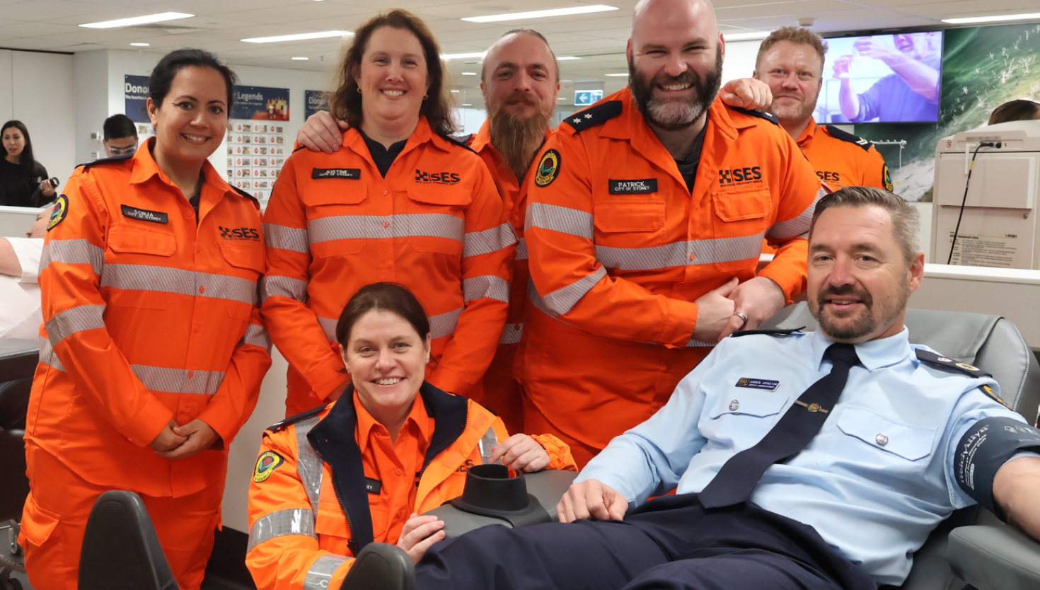 6 NSW SES volunteers surround Deputy Commissioner Damien Johnston donating blood 