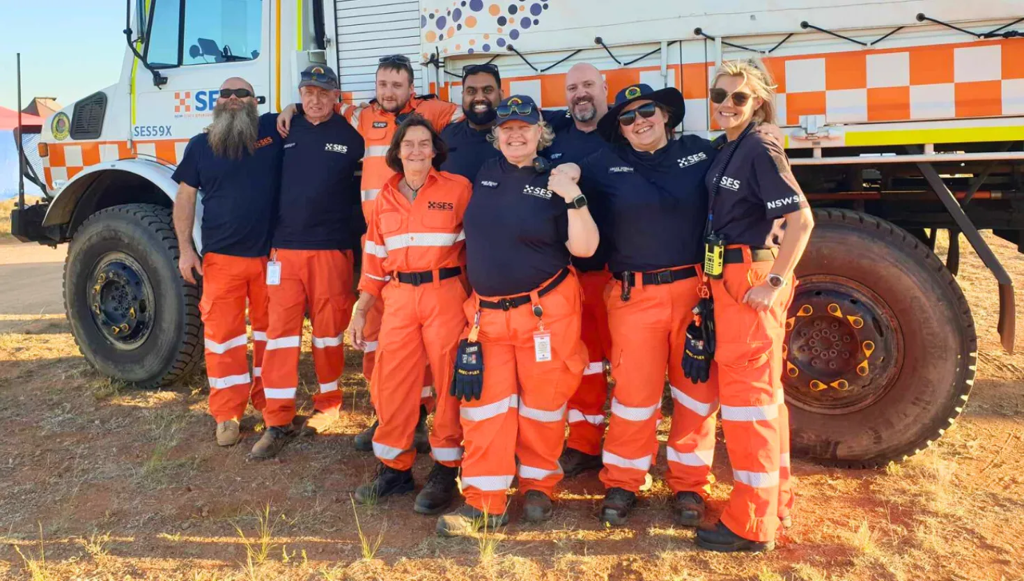 A group of 9 NSW SES volunteers standing in front of a Unimog vehicle