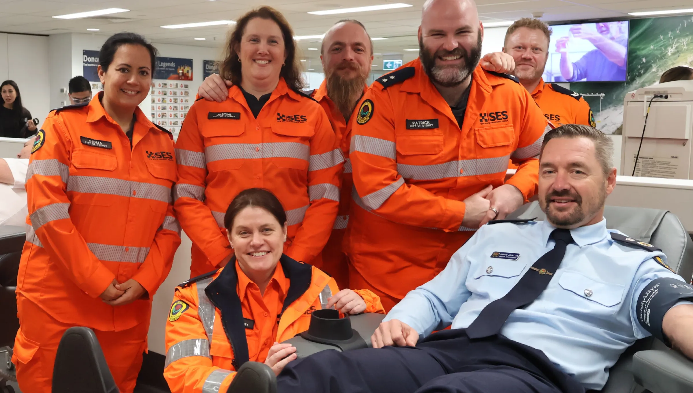 6 NSW SES volunteers surround Deputy Commissioner Damien Johnston donating blood 